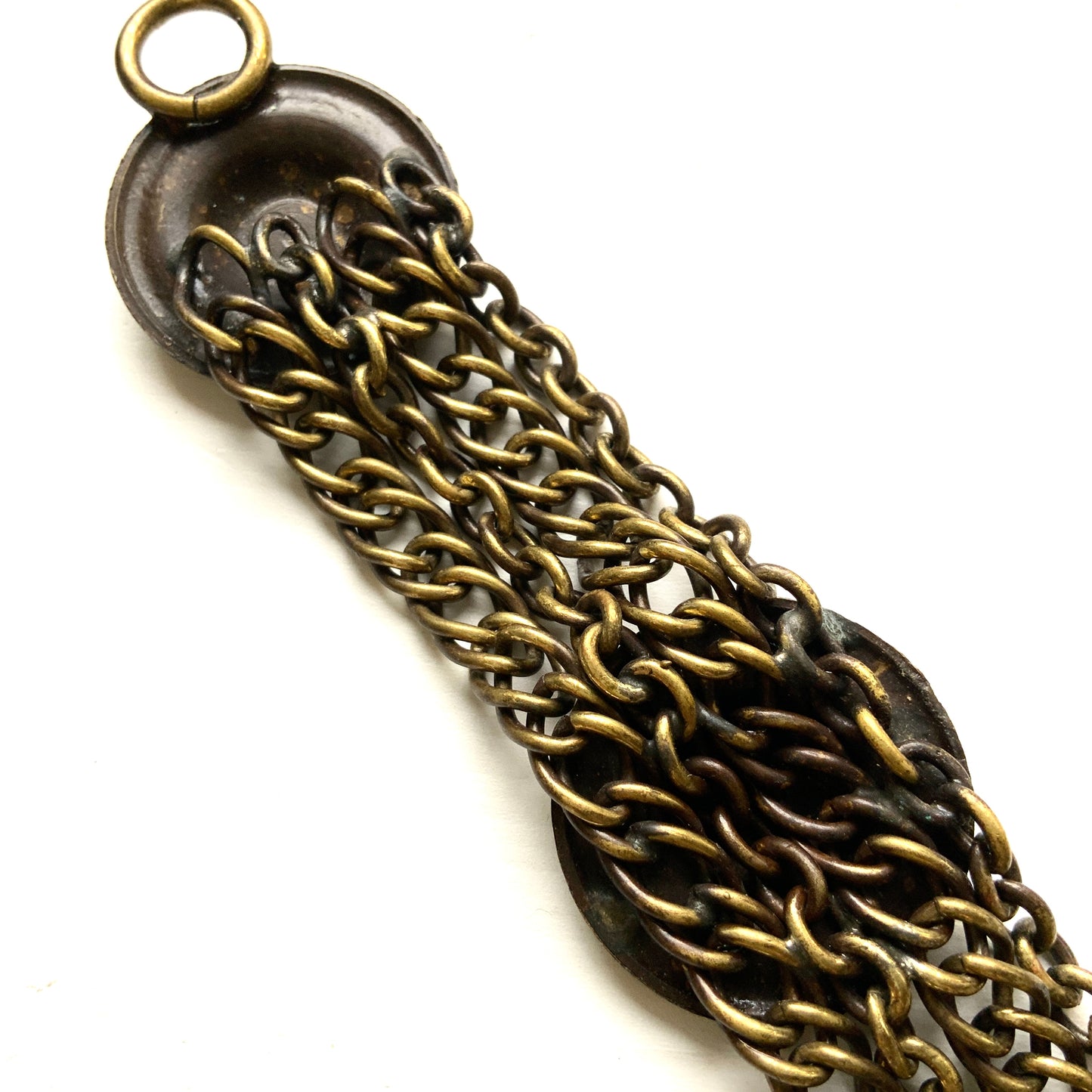 Brass bracelet featuring ornate floral discs linked with multiple chains. フローラルモチーフのメタルディスクと多連チェーンを組み合わせた、ブラス製ブレスレット。 