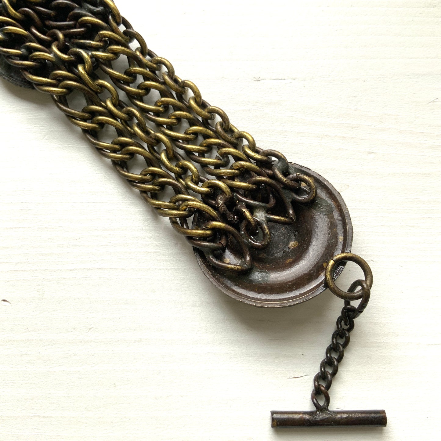 Brass bracelet featuring ornate floral discs linked with multiple chains. フローラルモチーフのメタルディスクと多連チェーンを組み合わせた、ブラス製ブレスレット。 