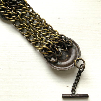 Brass bracelet featuring ornate floral discs linked with multiple chains. フローラルモチーフのメタルディスクと多連チェーンを組み合わせた、ブラス製ブレスレット。 