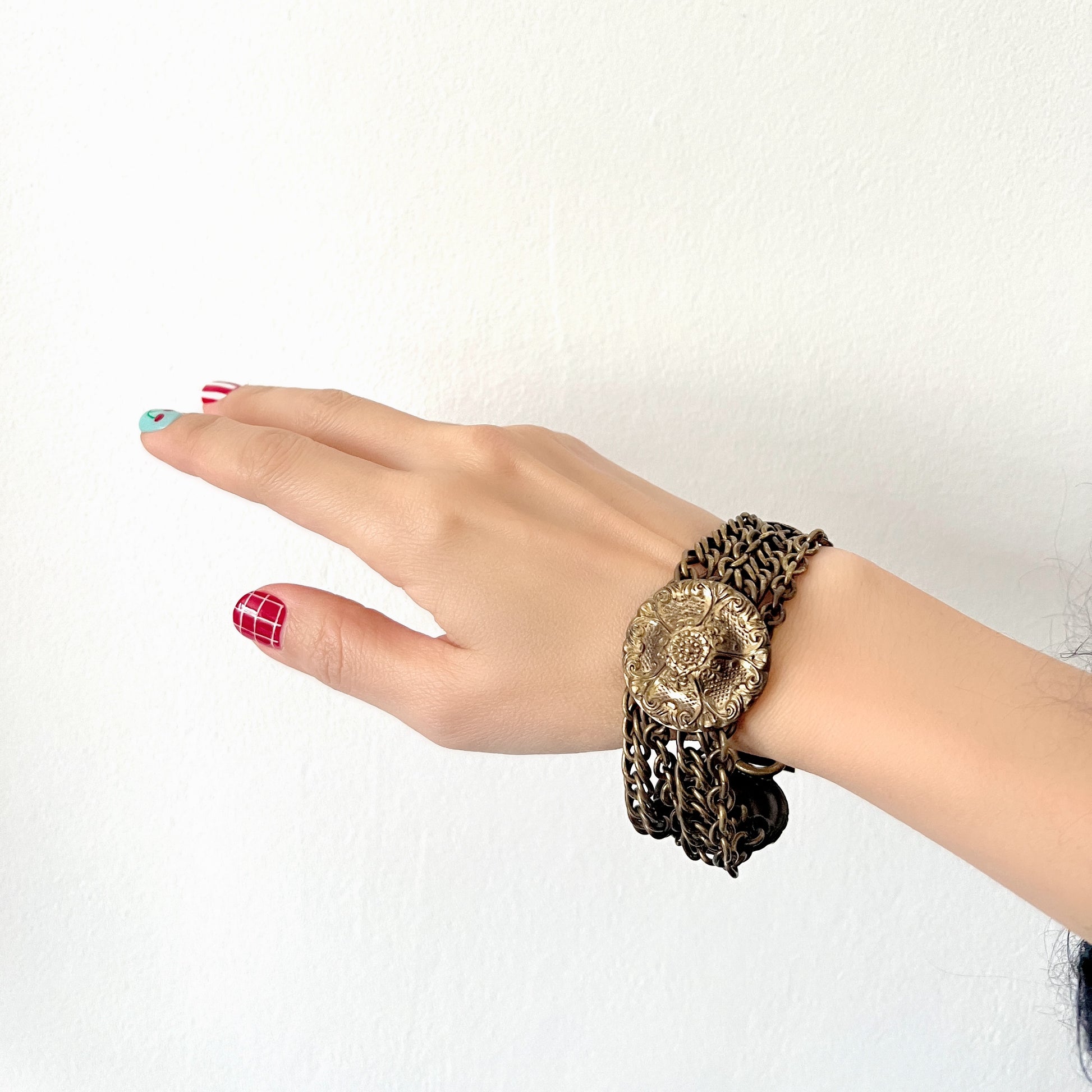 Brass bracelet featuring ornate floral discs linked with multiple chains. フローラルモチーフのメタルディスクと多連チェーンを組み合わせた、ブラス製ブレスレット。 