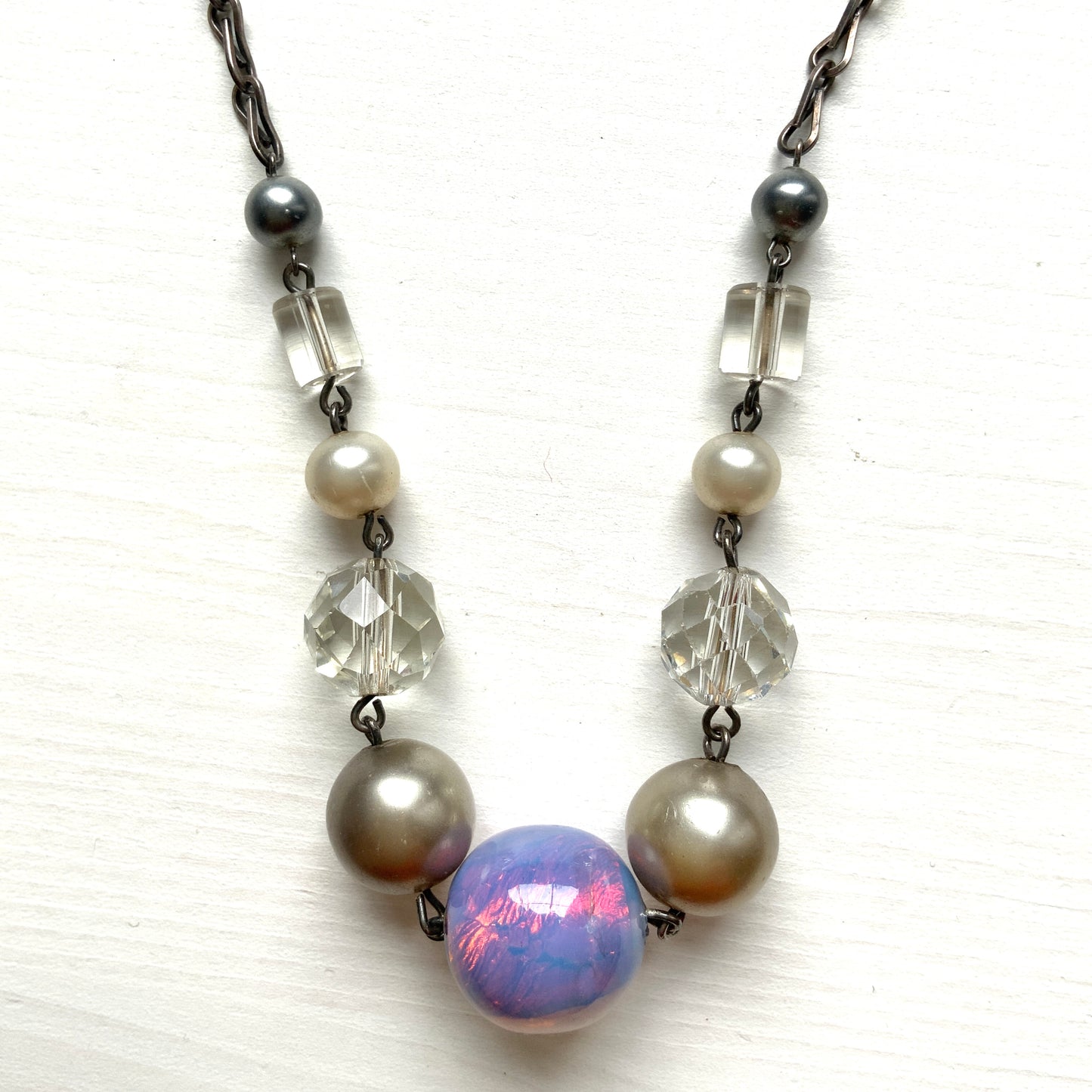A vintage necklace featuring opalescent glass enclosing pink and violet foil.  ピンクやパープルのフォイルを閉じ込めた、オパルセントガラスのヴィンテージネックレス。