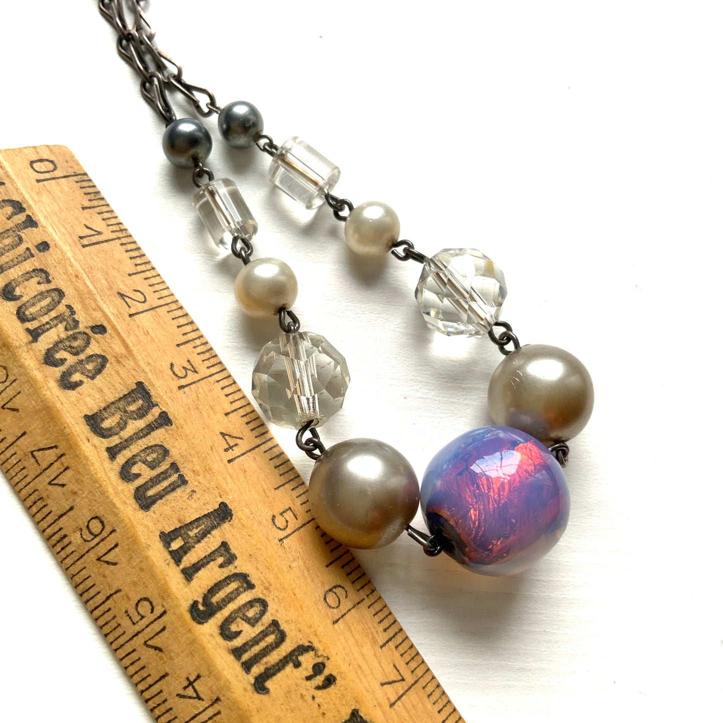 A vintage necklace featuring opalescent glass enclosing pink and violet foil.  ピンクやパープルのフォイルを閉じ込めた、オパルセントガラスのヴィンテージネックレス。