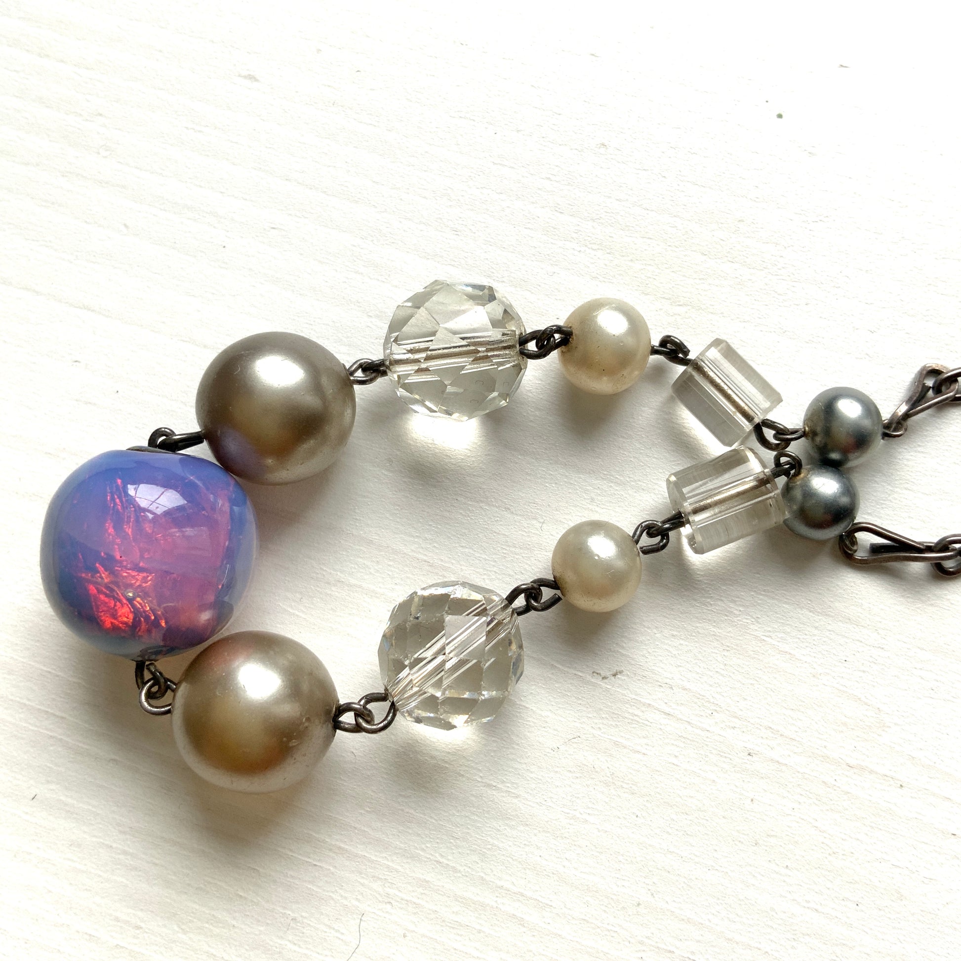 A vintage necklace featuring opalescent glass enclosing pink and violet foil.  ピンクやパープルのフォイルを閉じ込めた、オパルセントガラスのヴィンテージネックレス。