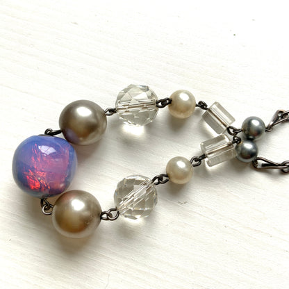 A vintage necklace featuring opalescent glass enclosing pink and violet foil.  ピンクやパープルのフォイルを閉じ込めた、オパルセントガラスのヴィンテージネックレス。