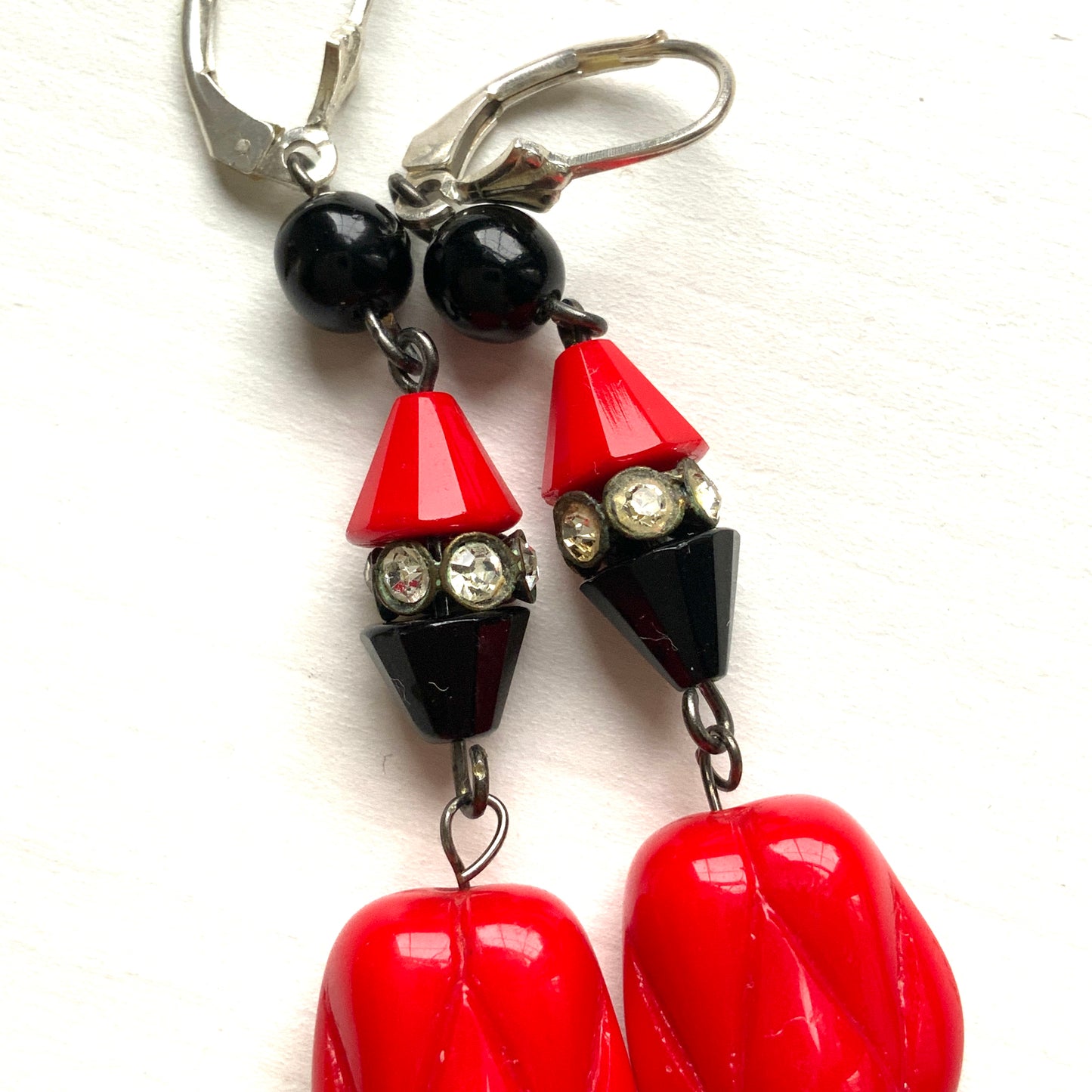 Earrings featuring faceted red and black cone beads, finished with a uniquely shaped red glass drop. ファセットカットの赤と黒のコーンビーズに、ユニークなフォルムのレッドガラスが揺れるピアス。