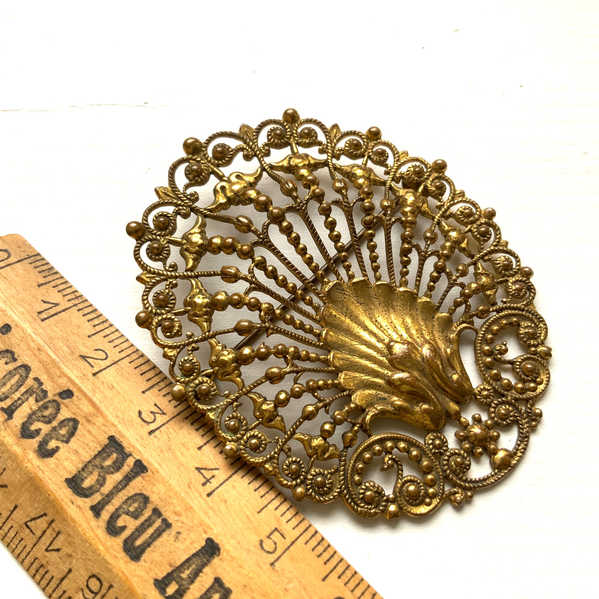 Delicate filigree brooch featuring a fan-like shape with a central shell motif. T 扇のようなフォルムにシェルモチーフをあしらった、繊細なフィリグリーのブローチ。
