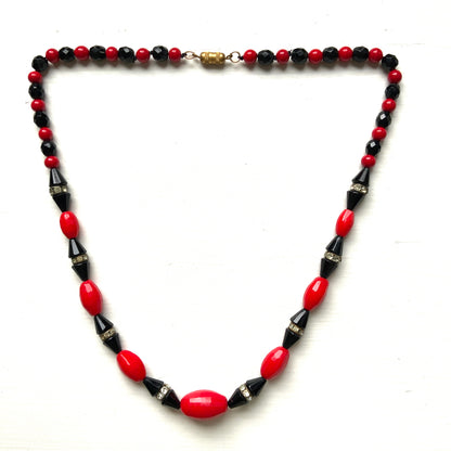 A striking 1930s necklace crafted from red and black glass. 赤と黒のガラスを組み合わせた、1930年代のネックレス。