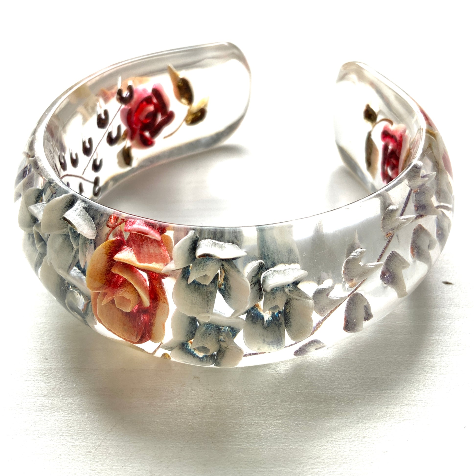 A vintage lucite bangle featuring carved and painted rose intaglios. クリアルーサイトに薔薇のインタリオが施されたヴィンテージバングル。