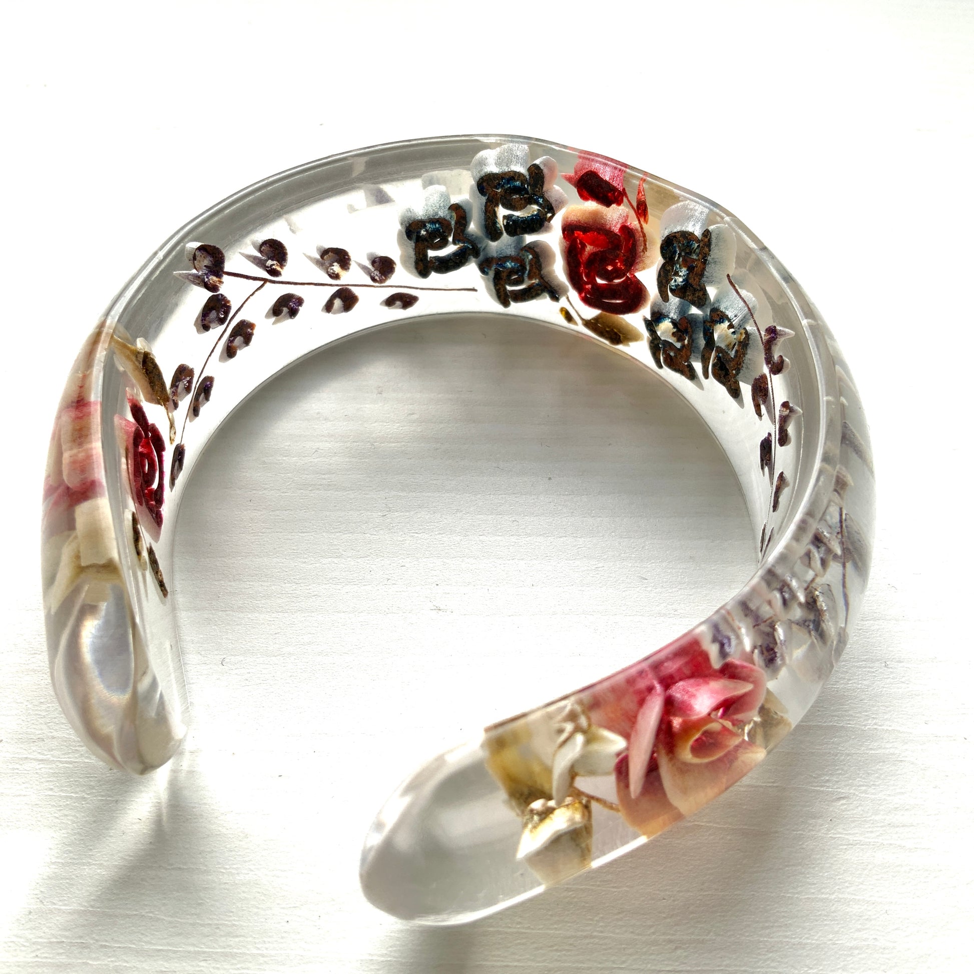 A vintage lucite bangle featuring carved and painted rose intaglios. クリアルーサイトに薔薇のインタリオが施されたヴィンテージバングル。