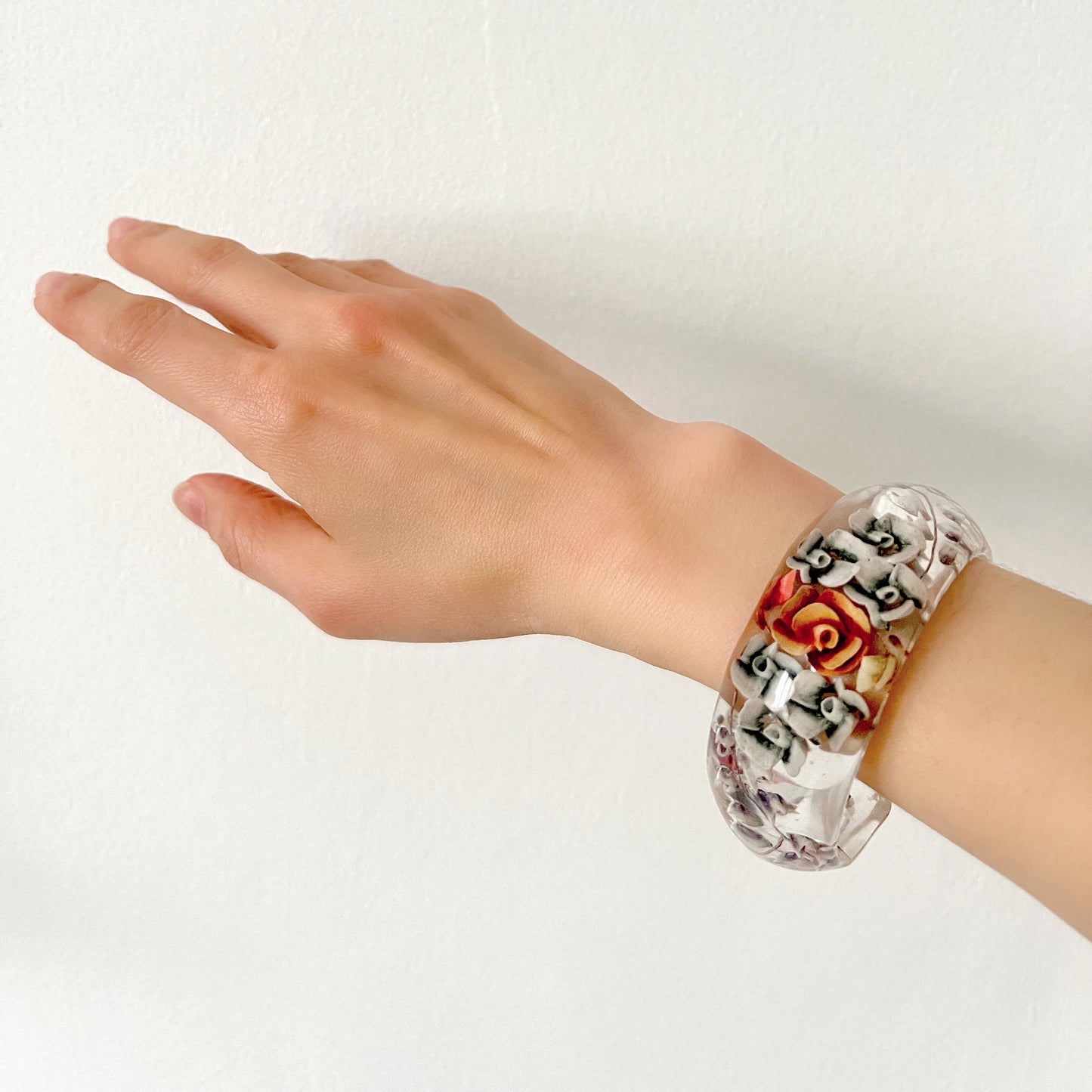 A vintage lucite bangle featuring carved and painted rose intaglios. クリアルーサイトに薔薇のインタリオが施されたヴィンテージバングル。