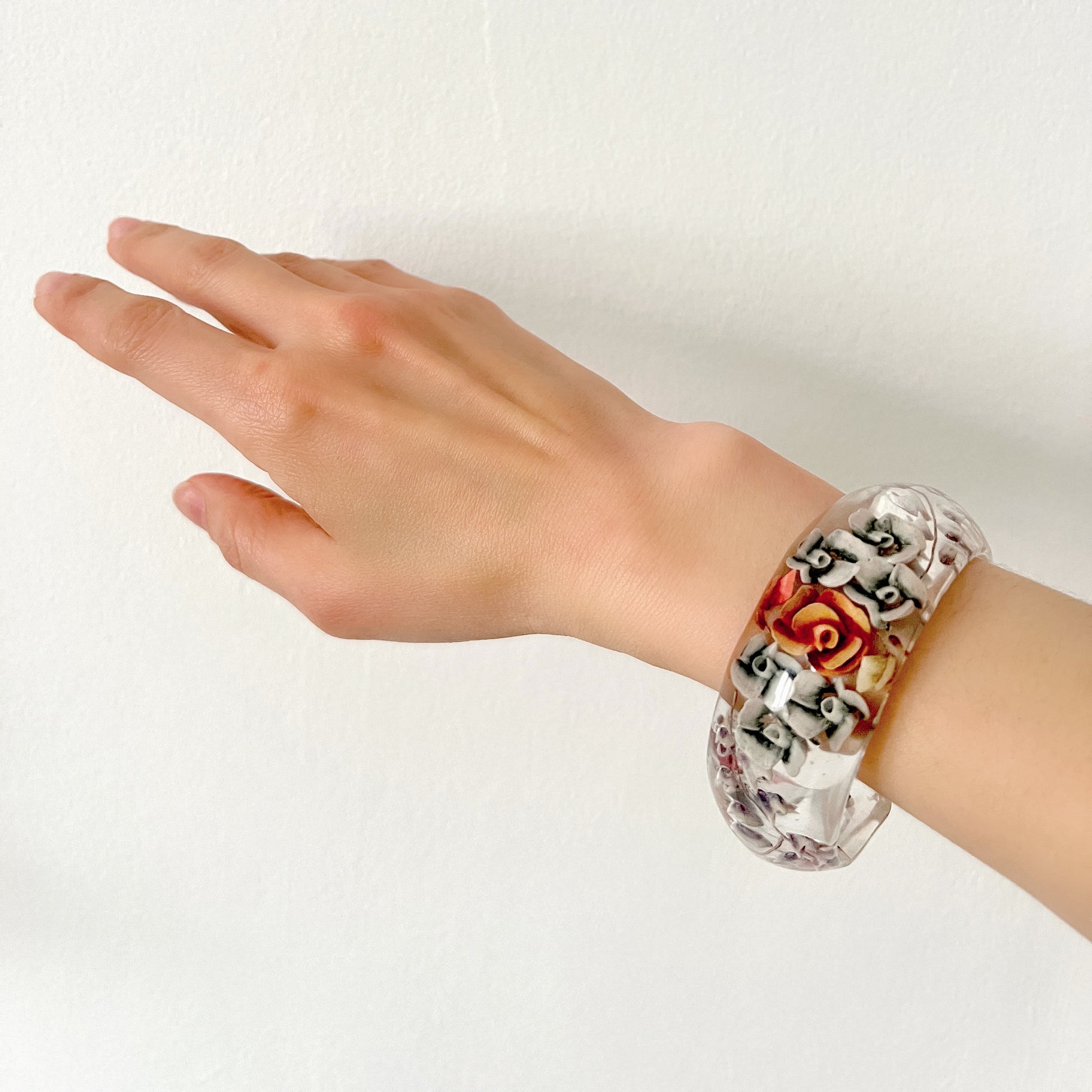 A vintage lucite bangle featuring carved and painted rose intaglios. クリアルーサイトに薔薇のインタリオが施されたヴィンテージバングル。