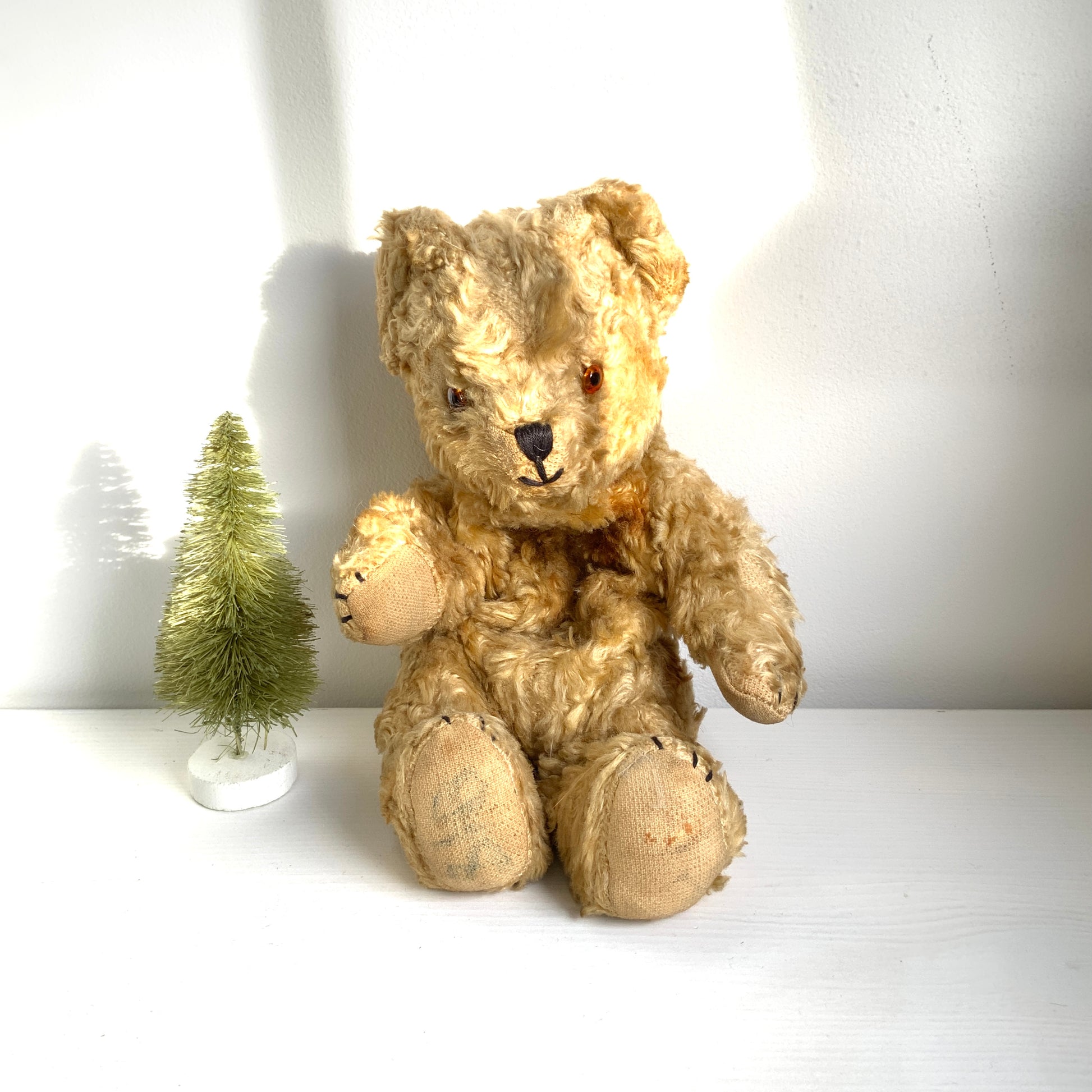 A small vintage teddy bear with the sweetest little smiling mouth.Softened by time, with slightly shrunken stuffing — all part of its charm. 小さな口元がにっこりと微笑んでいる、小さなヴィンテージテディベア。