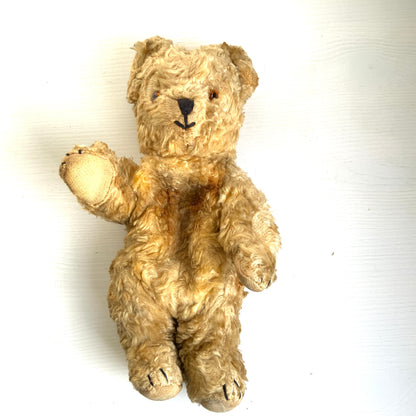 A small vintage teddy bear with the sweetest little smiling mouth.Softened by time, with slightly shrunken stuffing — all part of its charm. 小さな口元がにっこりと微笑んでいる、小さなヴィンテージテディベア。