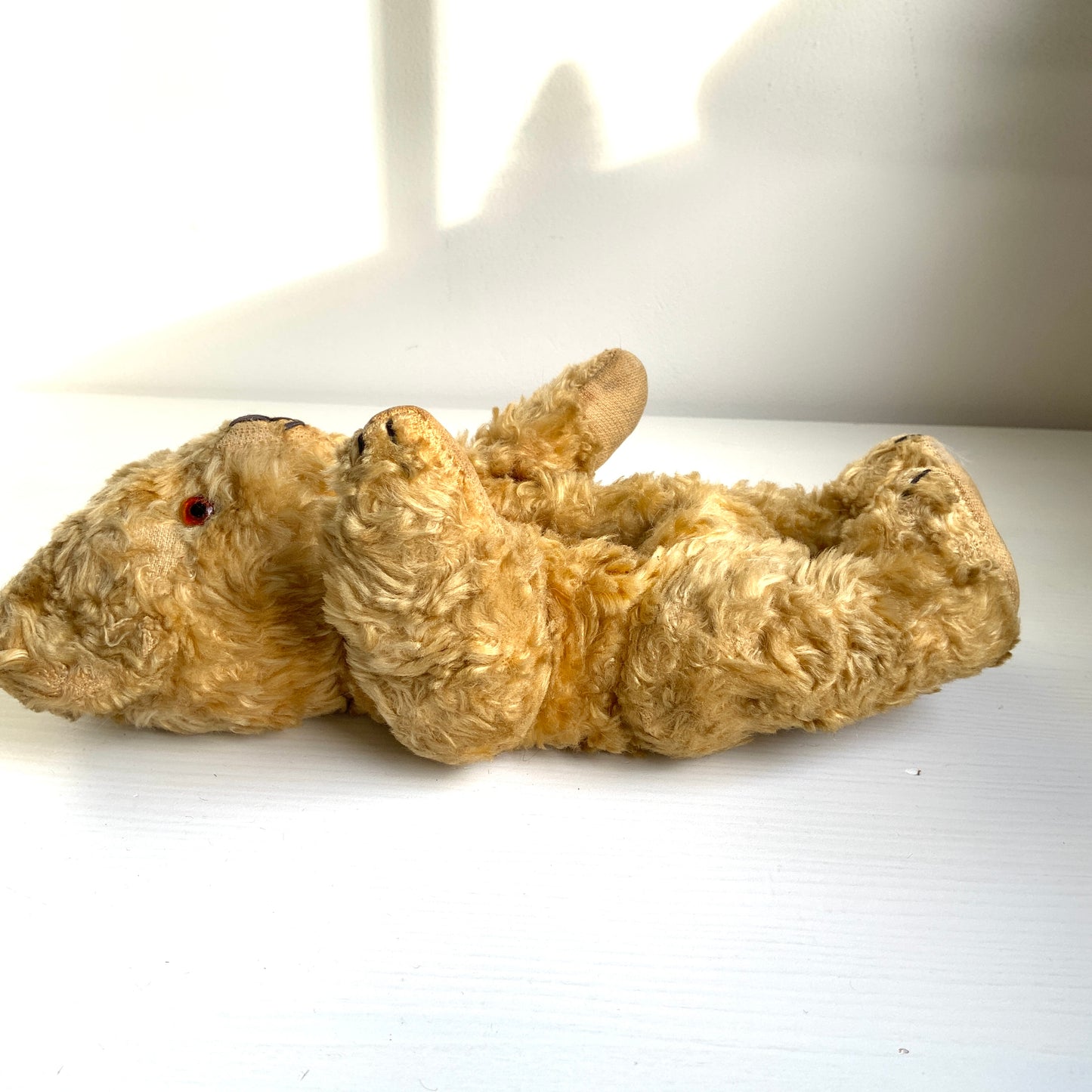 A small vintage teddy bear with the sweetest little smiling mouth.Softened by time, with slightly shrunken stuffing — all part of its charm. 小さな口元がにっこりと微笑んでいる、小さなヴィンテージテディベア。