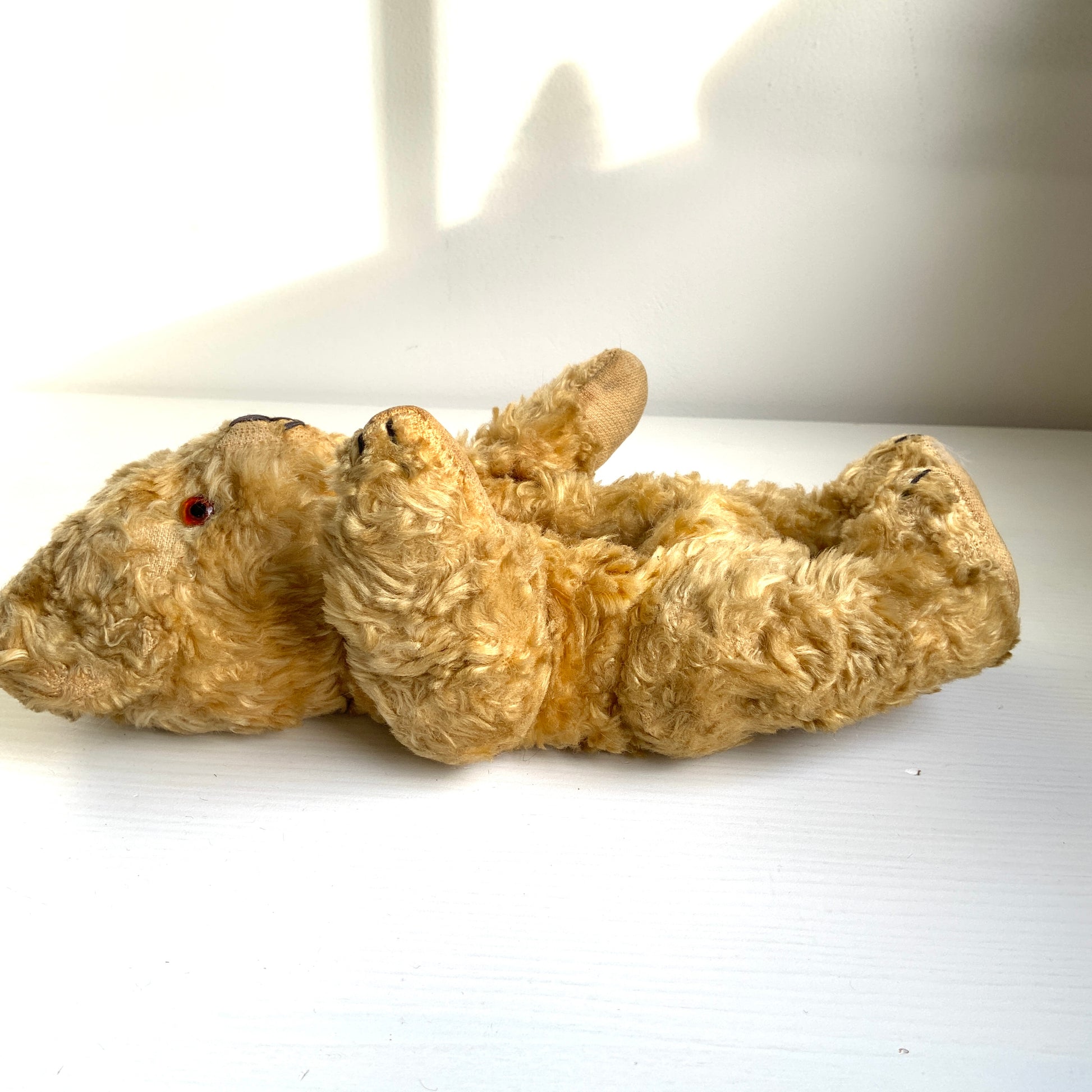 A small vintage teddy bear with the sweetest little smiling mouth.Softened by time, with slightly shrunken stuffing — all part of its charm. 小さな口元がにっこりと微笑んでいる、小さなヴィンテージテディベア。