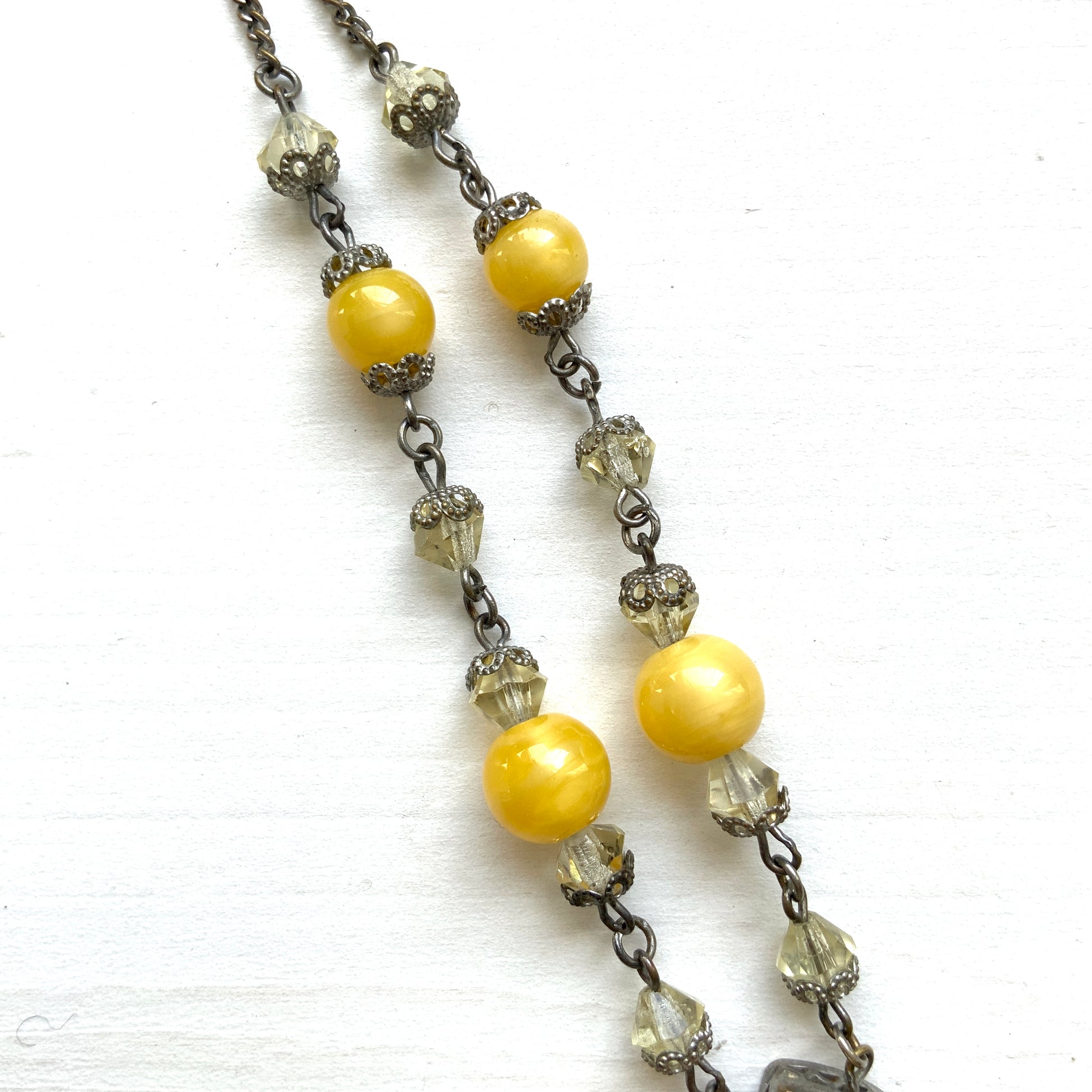 A 1930s necklace featuring soft butterscotch yellow satin glass, paired with delicate filigree details and clear glass accents. やわらかなバタースコッチイエローのサテンガラスに、繊細なフィリグリーパーツとクリアガラスを合わせた1930年代頃のネックレス。