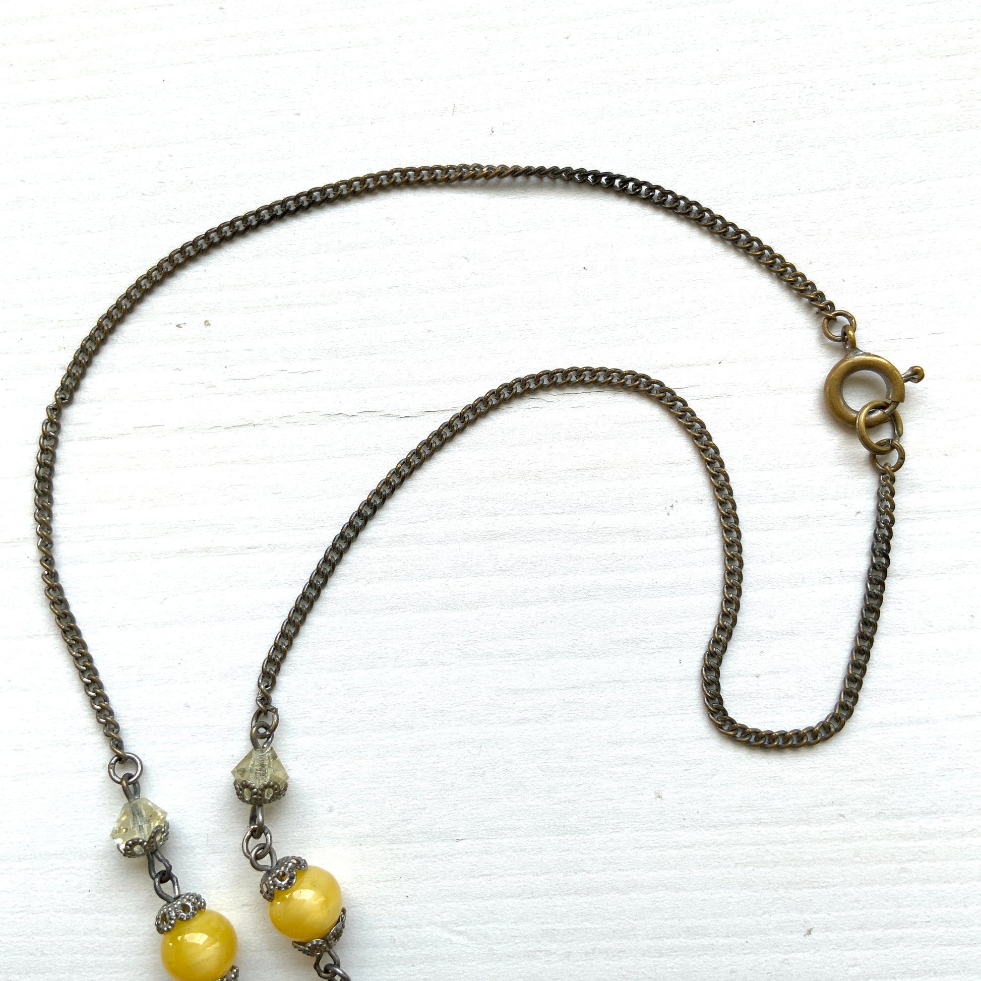 A 1930s necklace featuring soft butterscotch yellow satin glass, paired with delicate filigree details and clear glass accents. やわらかなバタースコッチイエローのサテンガラスに、繊細なフィリグリーパーツとクリアガラスを合わせた1930年代頃のネックレス。