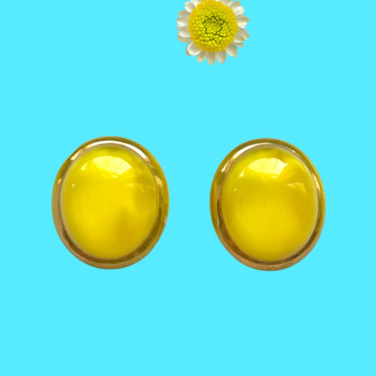 Lemon yellow satin glass clip-on earrings featuring large, smooth cabochons with a beautifully soft sheen unique to satin glass, reminiscent of silk or satin fabric. レモンイエローのサテンガラスのクリップイヤリング。