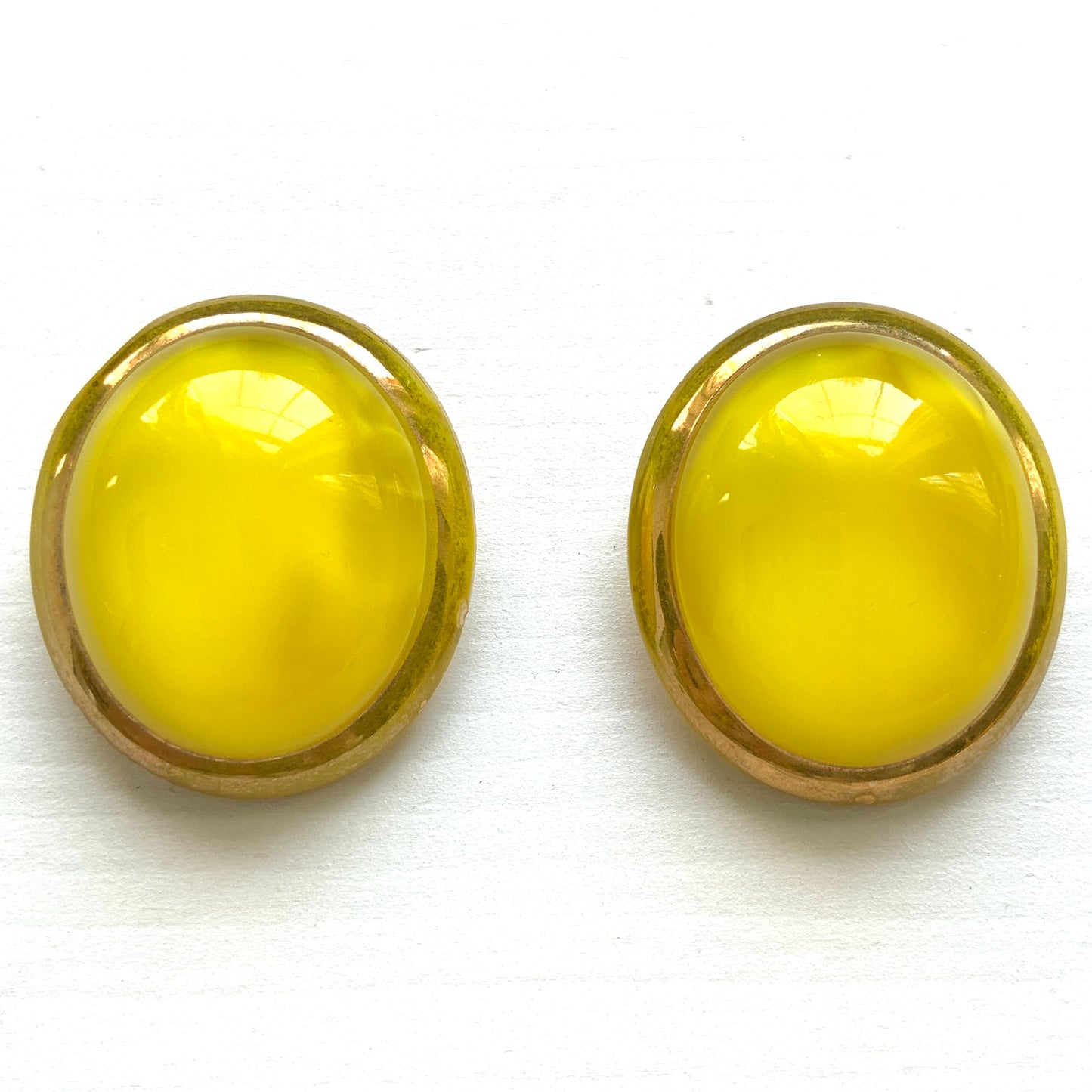 Lemon yellow satin glass clip-on earrings featuring large, smooth cabochons with a beautifully soft sheen unique to satin glass, reminiscent of silk or satin fabric. レモンイエローのサテンガラスのクリップイヤリング。
