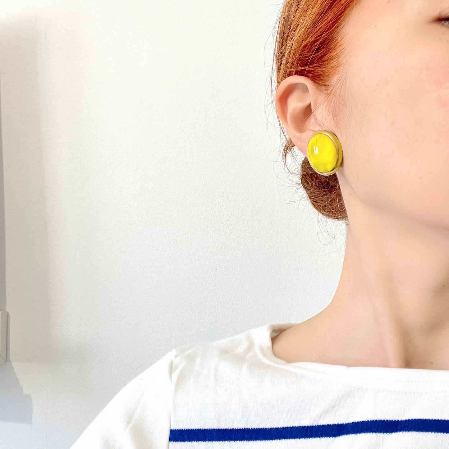 Lemon yellow satin glass clip-on earrings featuring large, smooth cabochons with a beautifully soft sheen unique to satin glass, reminiscent of silk or satin fabric. レモンイエローのサテンガラスのクリップイヤリング。