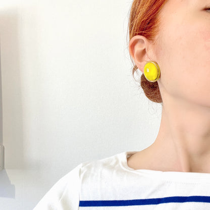 Lemon yellow satin glass clip-on earrings featuring large, smooth cabochons with a beautifully soft sheen unique to satin glass, reminiscent of silk or satin fabric. レモンイエローのサテンガラスのクリップイヤリング。
