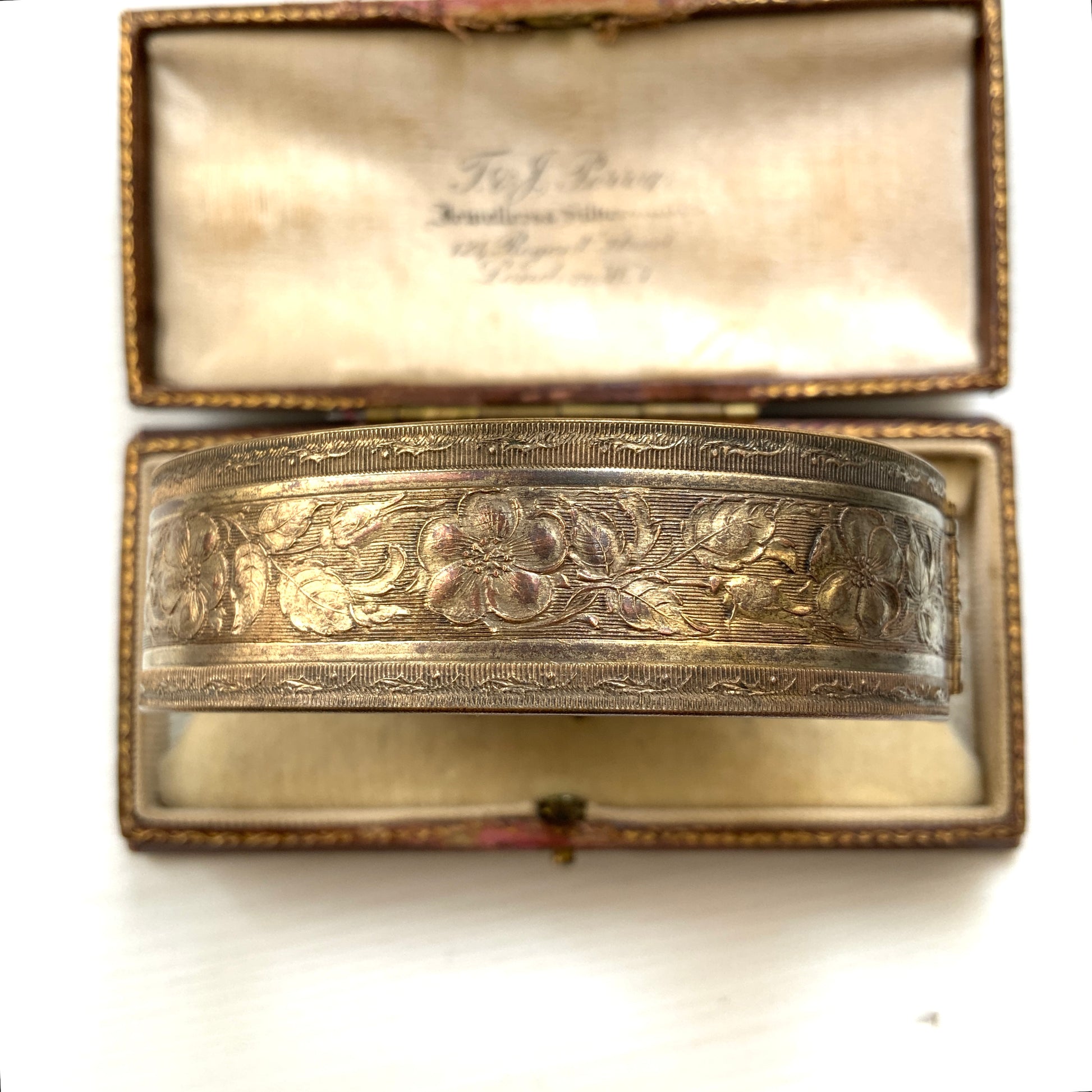 A decorative bangle featuring intricate floral motifs on gold-tone metal, with a filigree inspired design.  ゴールドトーンのメタルに、フィリグリー風の繊細な花模様があしらわれたデコラティブなバングル。