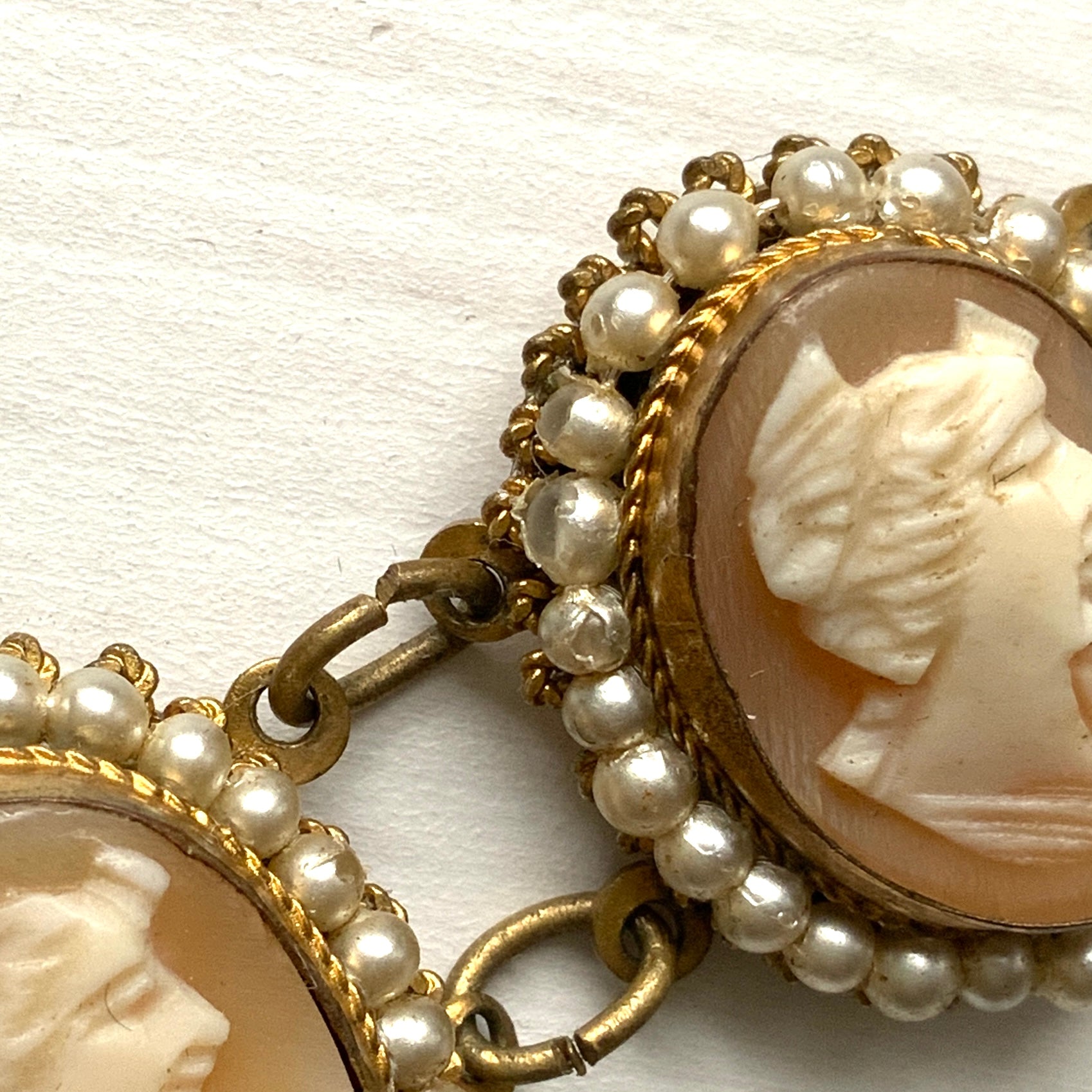 A bracelet lavishly set with seven shell cameos, each delicately framed with tiny glass pearls.  七つのシェルカメオを贅沢に連ねたブレスレット。 