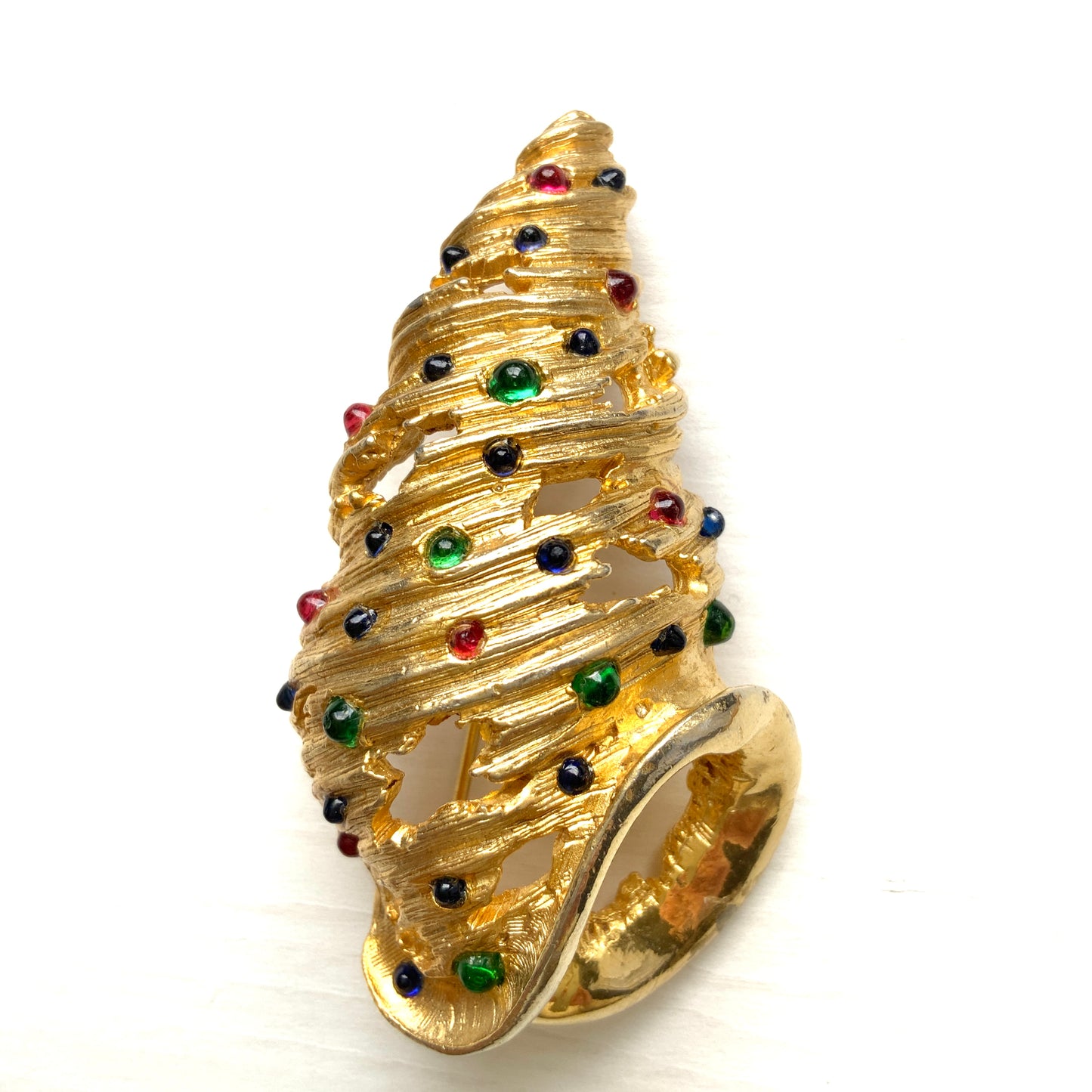 A vintage Alice Caviness brooch featuring a gold-tone spiral shell adorned with colourful glass cabochons. ゴールドトーンの巻貝に、カラフルなグラスカボションがあしらわれた、Alice Caviness のヴィンテージブローチ。