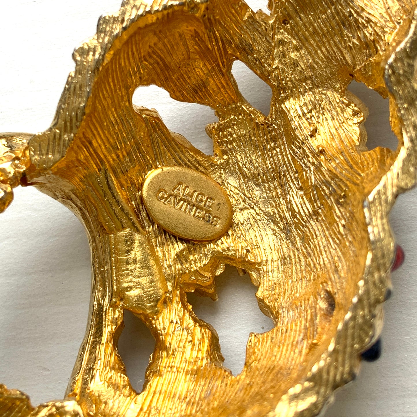 A vintage Alice Caviness brooch featuring a gold-tone spiral shell adorned with colourful glass cabochons. ゴールドトーンの巻貝に、カラフルなグラスカボションがあしらわれた、Alice Caviness のヴィンテージブローチ。