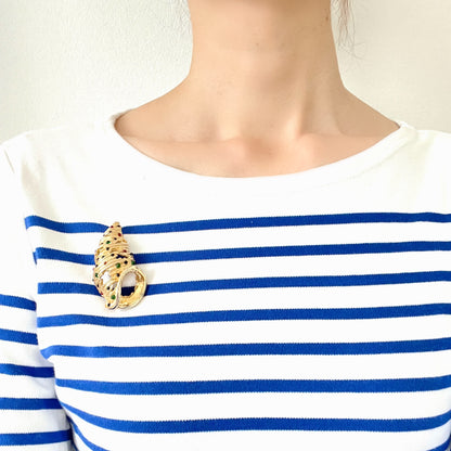 A vintage Alice Caviness brooch featuring a gold-tone spiral shell adorned with colourful glass cabochons. ゴールドトーンの巻貝に、カラフルなグラスカボションがあしらわれた、Alice Caviness のヴィンテージブローチ。