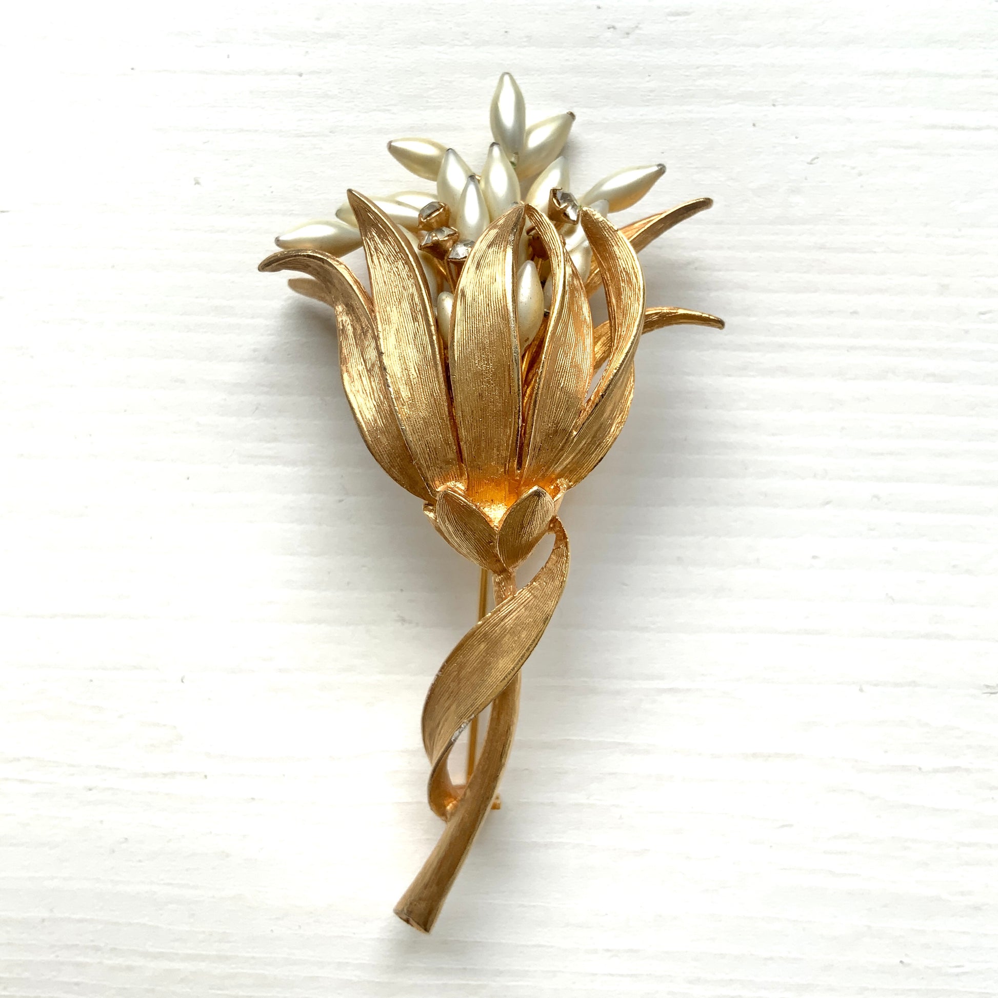 A vintage floral brooch featuring beautiful gold tones and glass pearls. ゴールドトーンとグラスパールが美しいフラワーモチーフのヴィンテージブローチ。