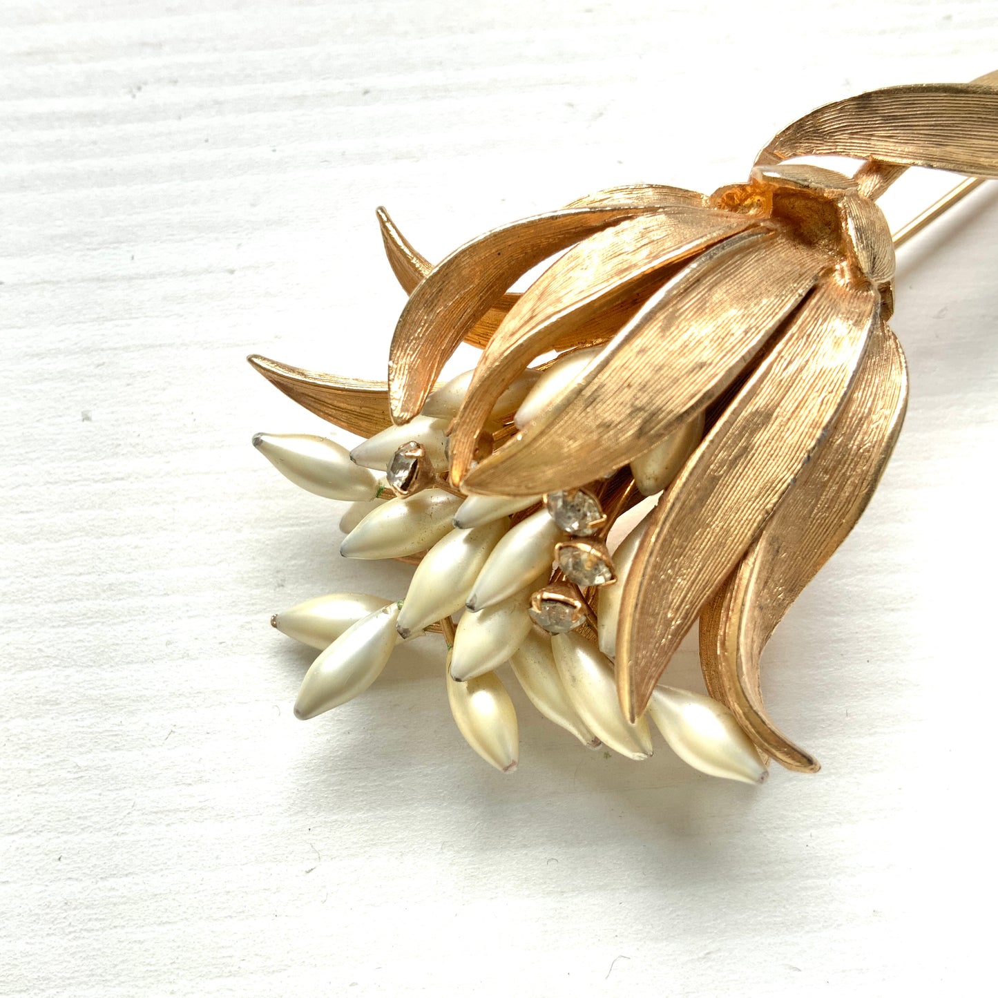 A vintage floral brooch featuring beautiful gold tones and glass pearls. ゴールドトーンとグラスパールが美しいフラワーモチーフのヴィンテージブローチ。