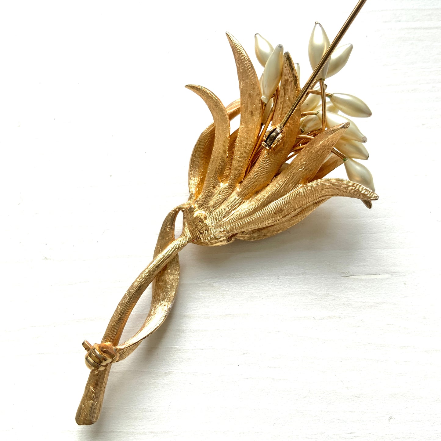 A vintage floral brooch featuring beautiful gold tones and glass pearls. ゴールドトーンとグラスパールが美しいフラワーモチーフのヴィンテージブローチ。