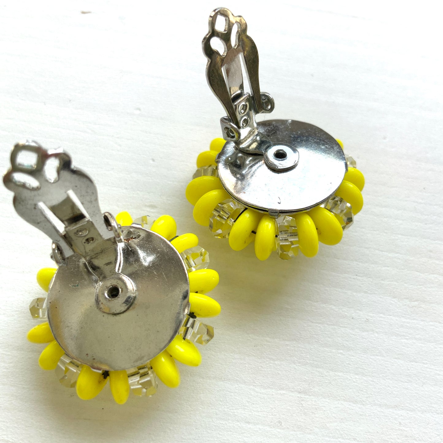 Laguna clip-on earrings featuring vibrant neon yellow beads paired with faceted clear glass accents. 鮮やかなネオンイエローとクリアビーズを組み合わせた、Lagunaのクリップイヤリング。