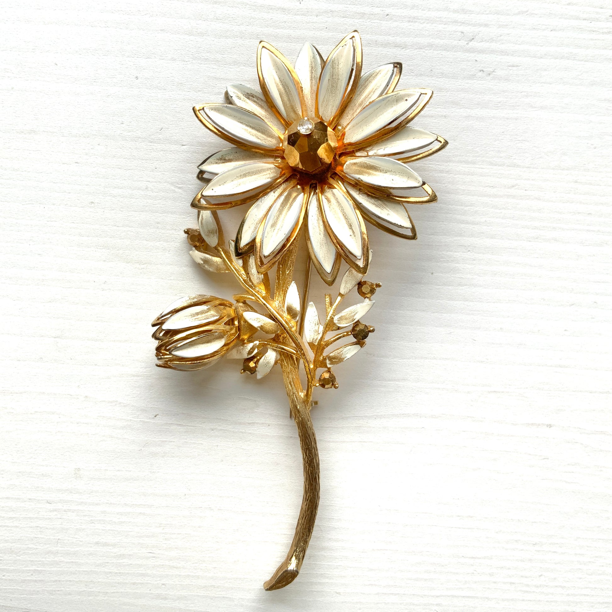 A large vintage brooch featuring white enamel flowers. ホワイトのエナメルフラワーがあしらわれた大ぶりのヴィンテージブローチ。 