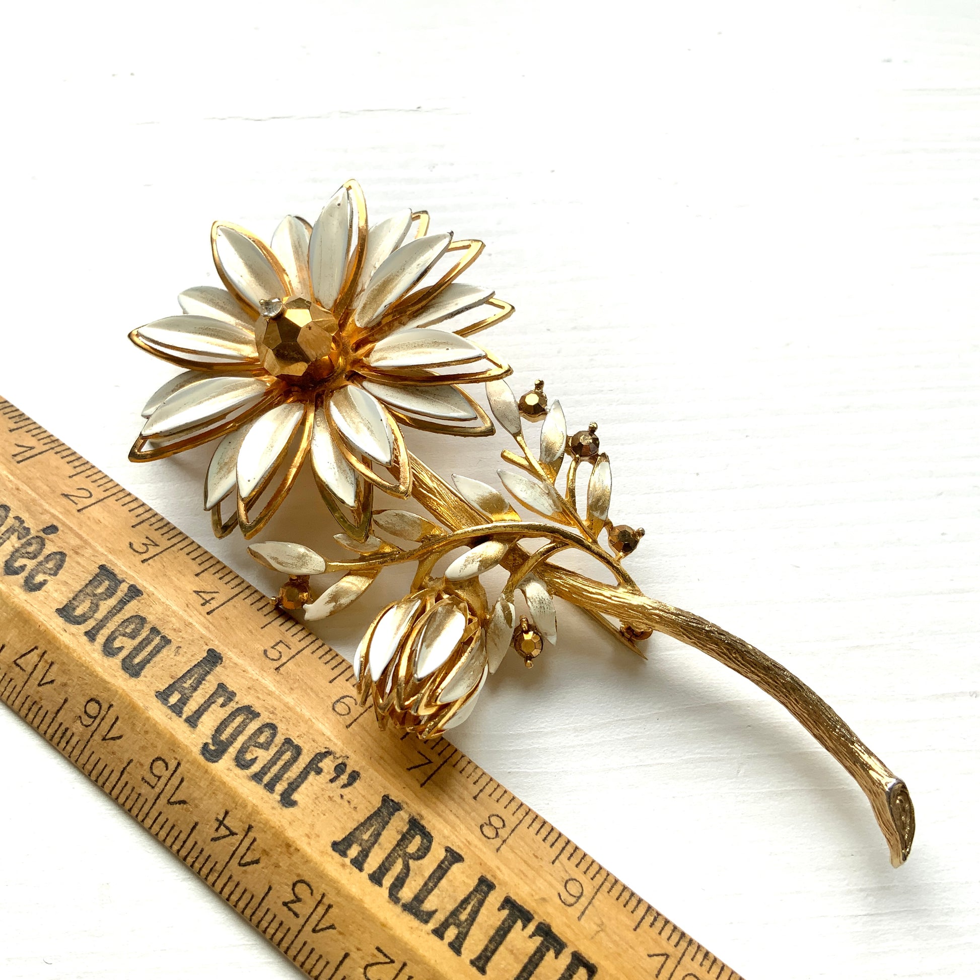 A large vintage brooch featuring white enamel flowers. ホワイトのエナメルフラワーがあしらわれた大ぶりのヴィンテージブローチ。 