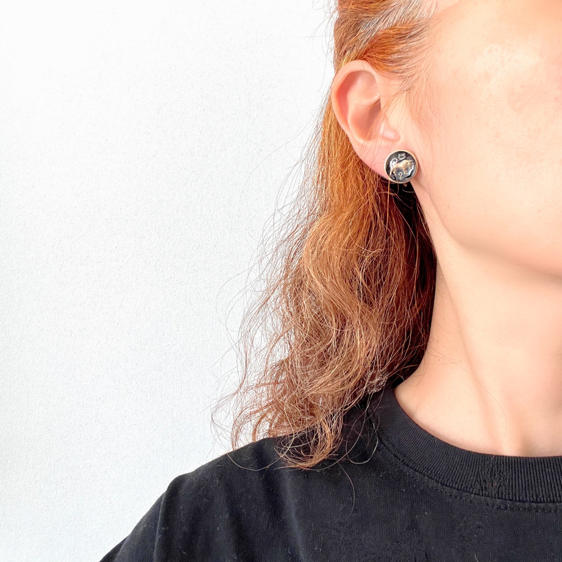 Screw-back earrings featuring an reverse carved design of a Taurus bull . 黒地にゴールドトーンで牡牛とそのシンボルが裏彫りされた、ヴィンテージのスクリューイヤリング。 