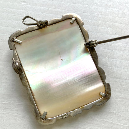 A brooch featuring a cameo of a lady’s profile carved in black mother of pearl, set against a white mother of pearl base. 白蝶貝をベースに、黒蝶貝で女性の横顔カメオをあしらったブローチ。 