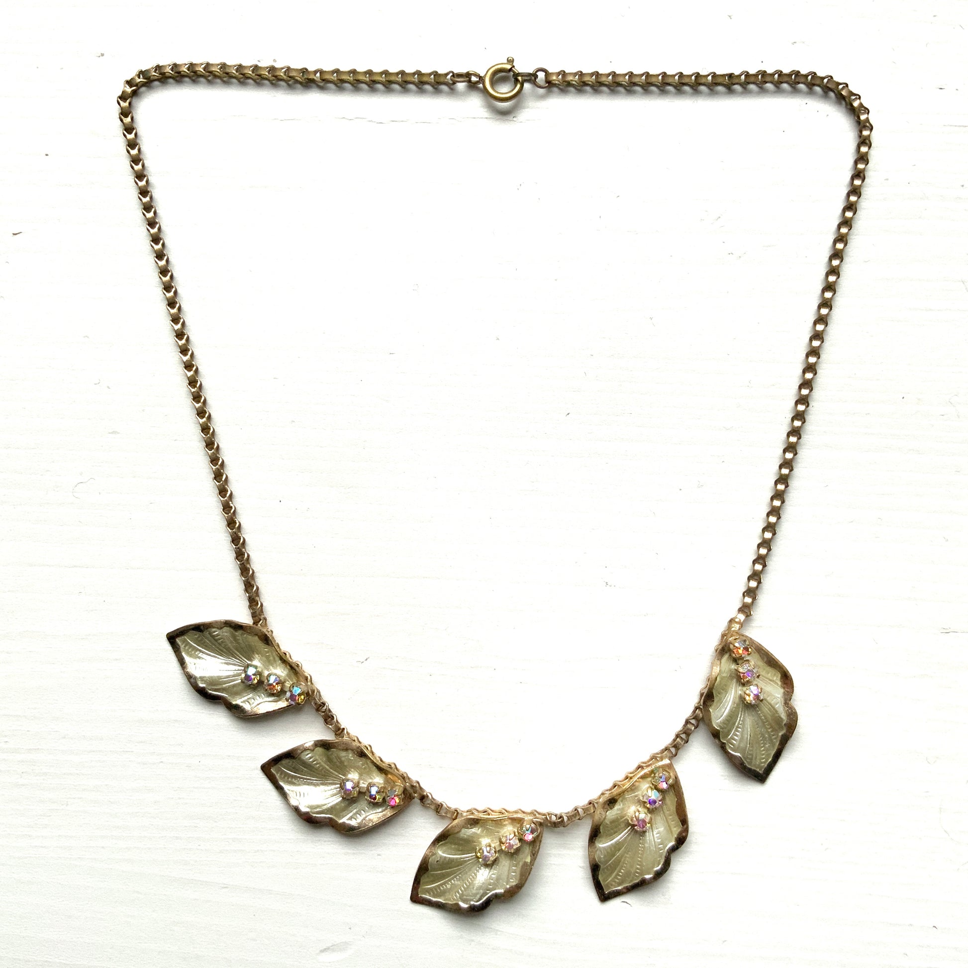 A graceful vintage necklace featuring leaf motifs in gold-tone metal with pearl white enamel detailing. エナメルリーフ×オーロラストーンのネックレス。