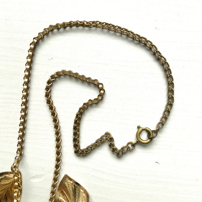 A graceful vintage necklace featuring leaf motifs in gold-tone metal with pearl white enamel detailing. エナメルリーフ×オーロラストーンのネックレス。