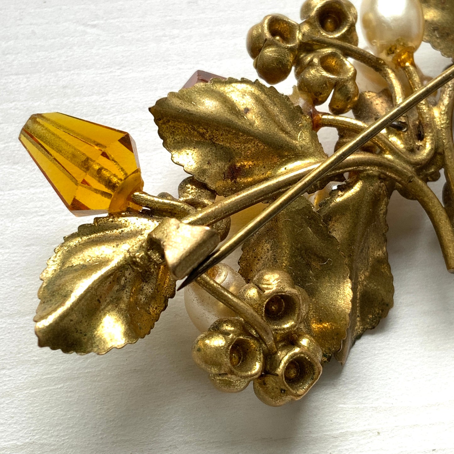 A floral brooch adorned with green enamel leaves, amber glass beads, and faux pearls. グリーンのエナメルリーフに、アンバーグラスビーズやグラスパールをあしらったフラワーブローチ。