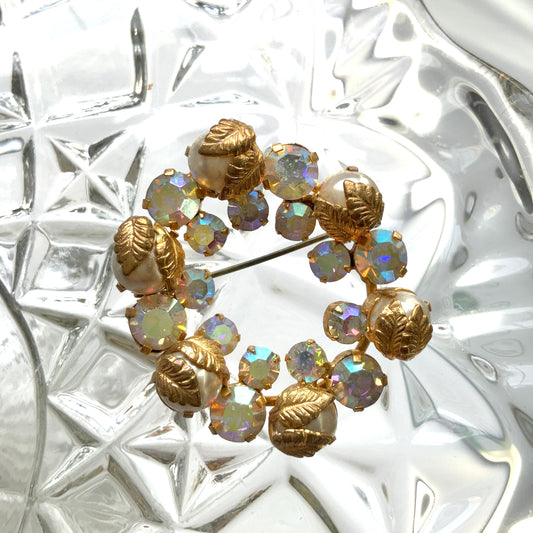 A vintage wreath brooch combining aurora borealis rhinestones, faux pearls and gold-tone leaves. オーロラストーン×パール×ゴールドトーンリーフのリースブローチ。