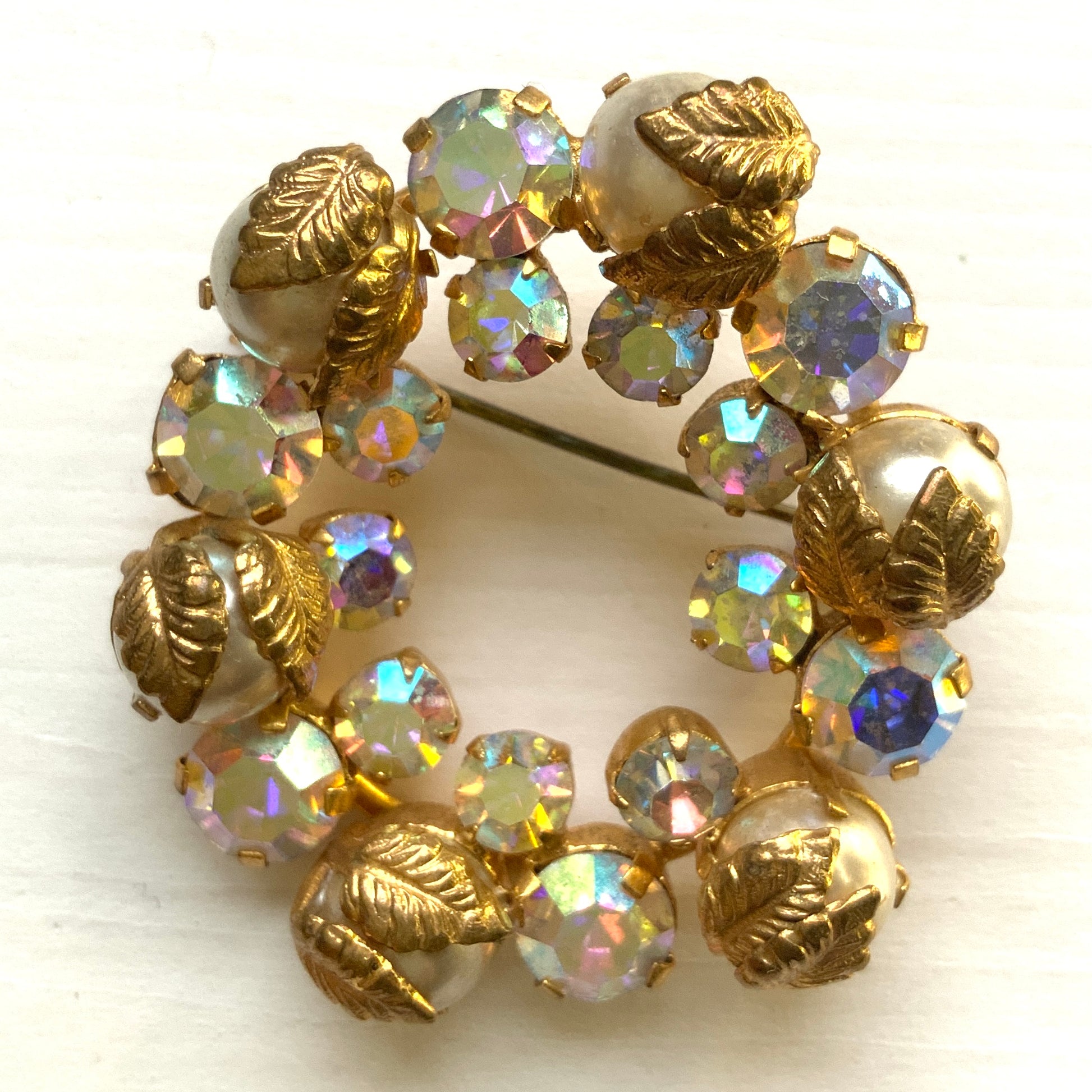 A vintage wreath brooch combining aurora borealis rhinestones, faux pearls and gold-tone leaves. オーロラストーン×パール×ゴールドトーンリーフのリースブローチ。