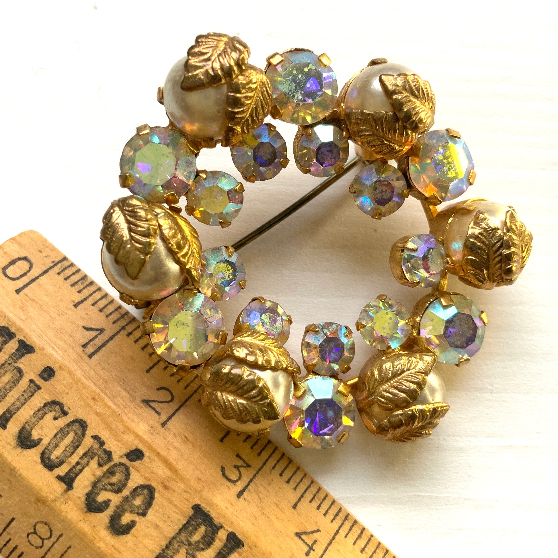 A vintage wreath brooch combining aurora borealis rhinestones, faux pearls and gold-tone leaves. オーロラストーン×パール×ゴールドトーンリーフのリースブローチ。