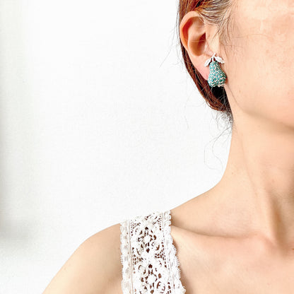 White pear-shaped clip earrings set with turquoise glass stones. ターコイズカラーのガラスストーンが散りばめられた、白い洋梨モチーフのクリップイヤリング。