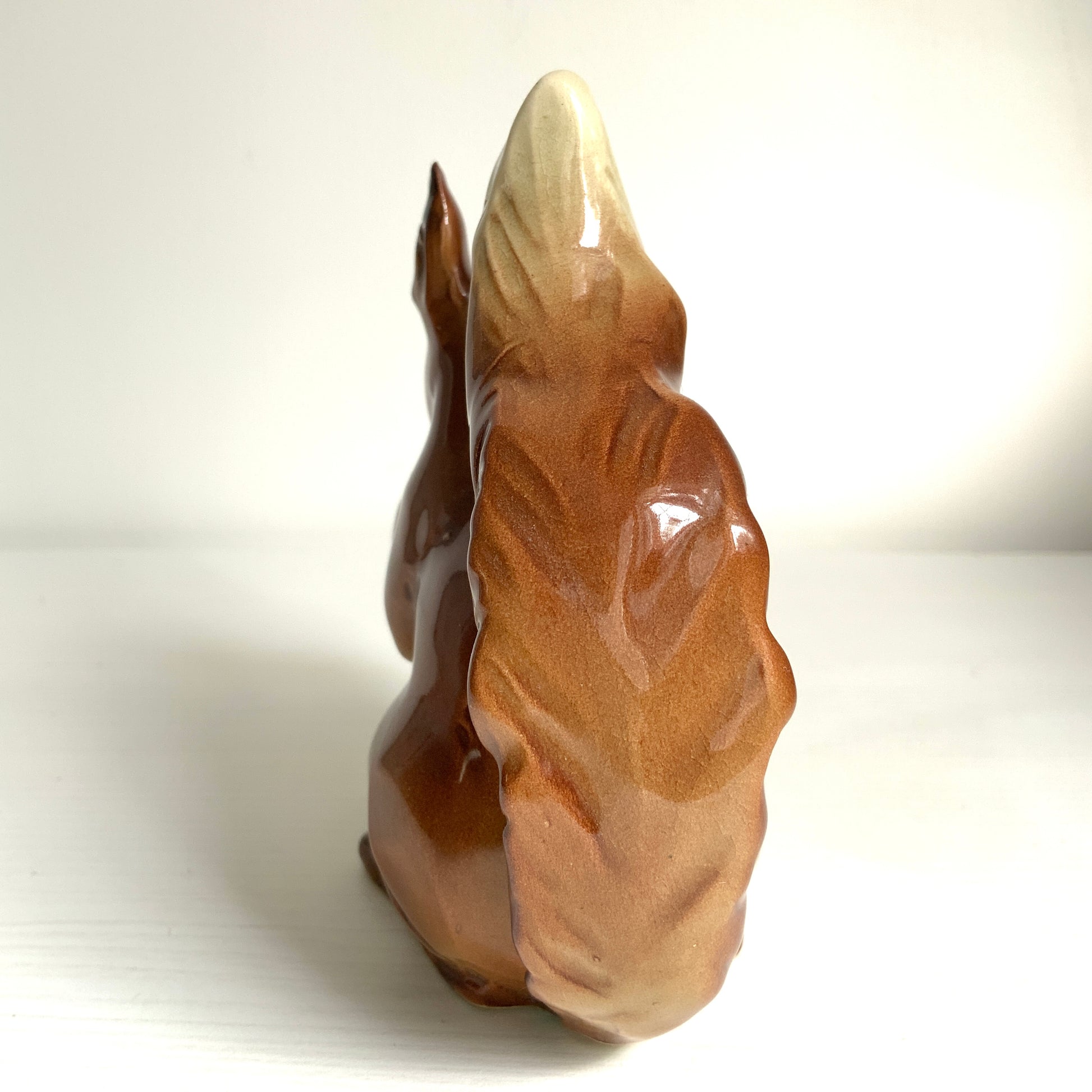 A charming ceramic squirrel figurine holding a nut. ナッツを抱えた、愛らしいセラミック製のリスのフィギュリン。