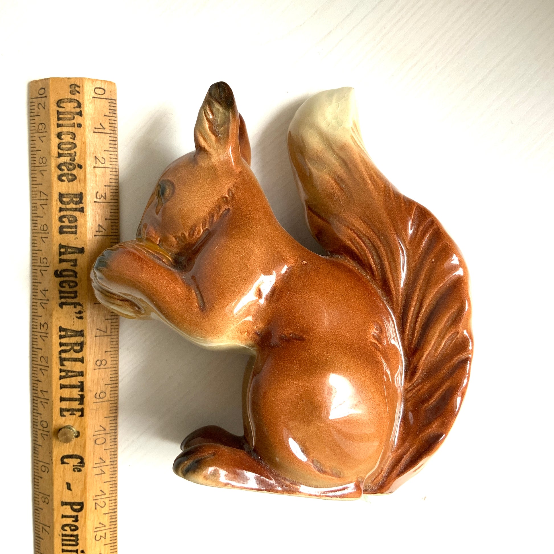 A charming ceramic squirrel figurine holding a nut. ナッツを抱えた、愛らしいセラミック製のリスのフィギュリン。