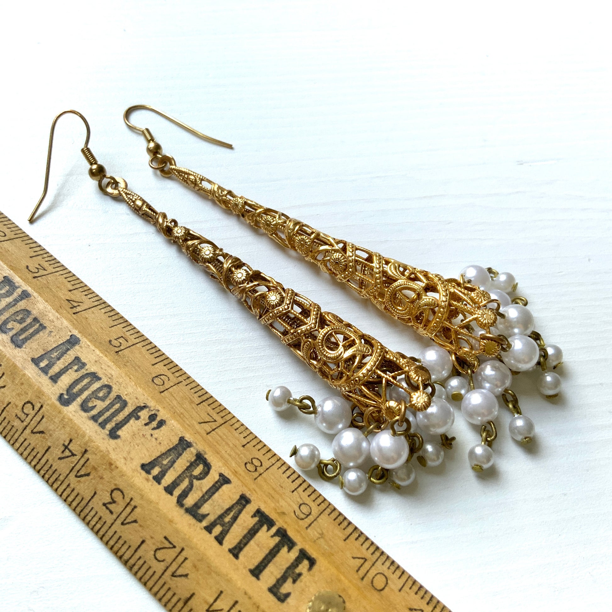 These earrings feature gold-tone filigree cones with faux pearl fringes that dangle elegantly.  ゴールドトーンのフィリグリーのコーンにフォーパールのフリンジが揺れるピアス。