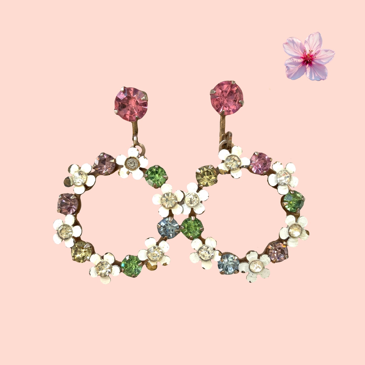 A pair of screw-back earrings featuring delicate white enamel flowers and a dangling hoop of rhinestones.  小さな白いエナメルの花とラインストーンのフープが揺れるスクリューイヤリング。 