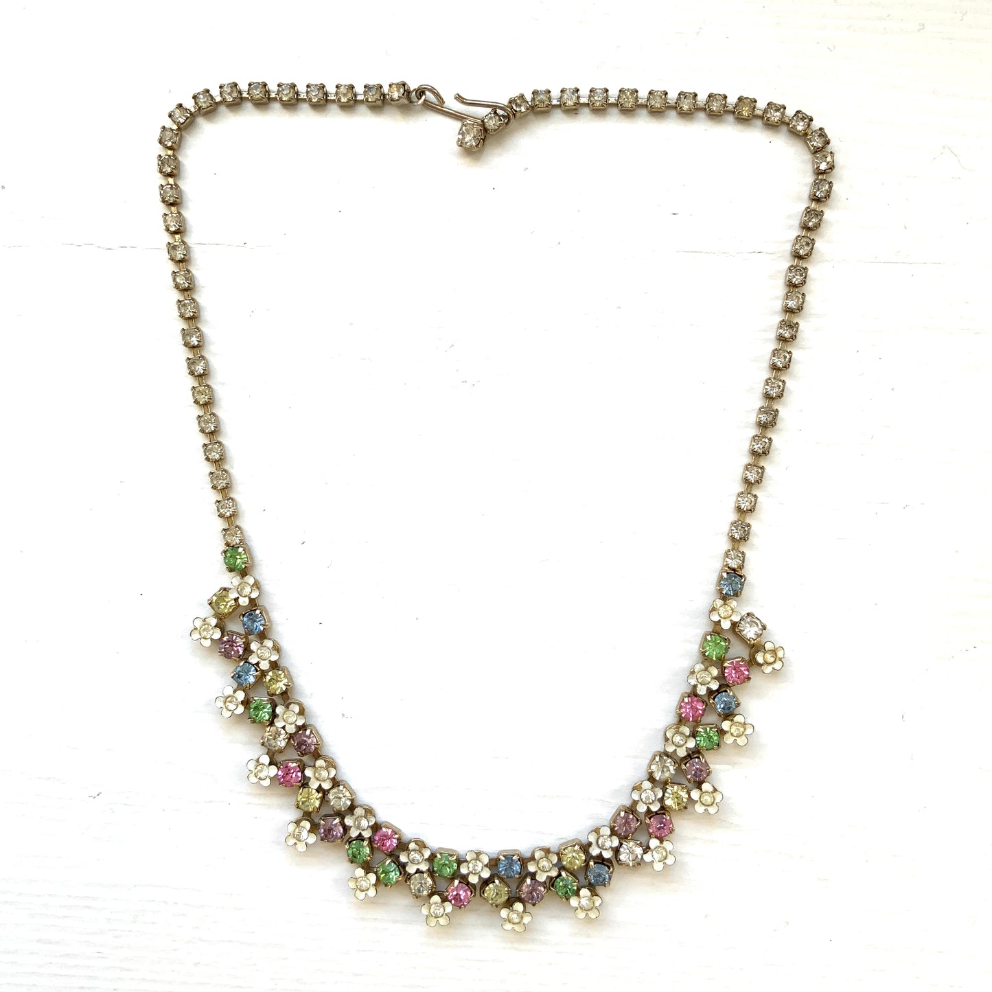 A vintage necklace adorned with white enamel flowers and colourful rhinestones.白いエナメルのお花とカラフルなラインストーンが並んだネックレス。
